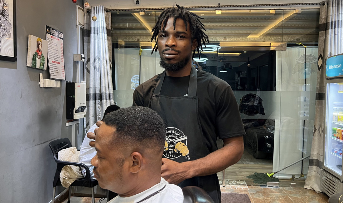 Der Friseur Nana Kwame mit einem Kunden in seinem Salon.