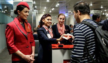 Drei türkische Stewardessen geben einem Passagier seinen Pass samt Boardingpass. 