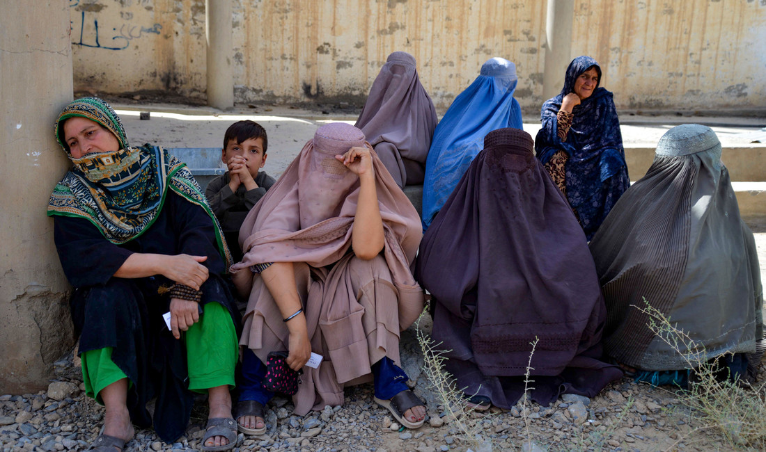 Frauen in Burkas sitzen auf dem Boden und warten.